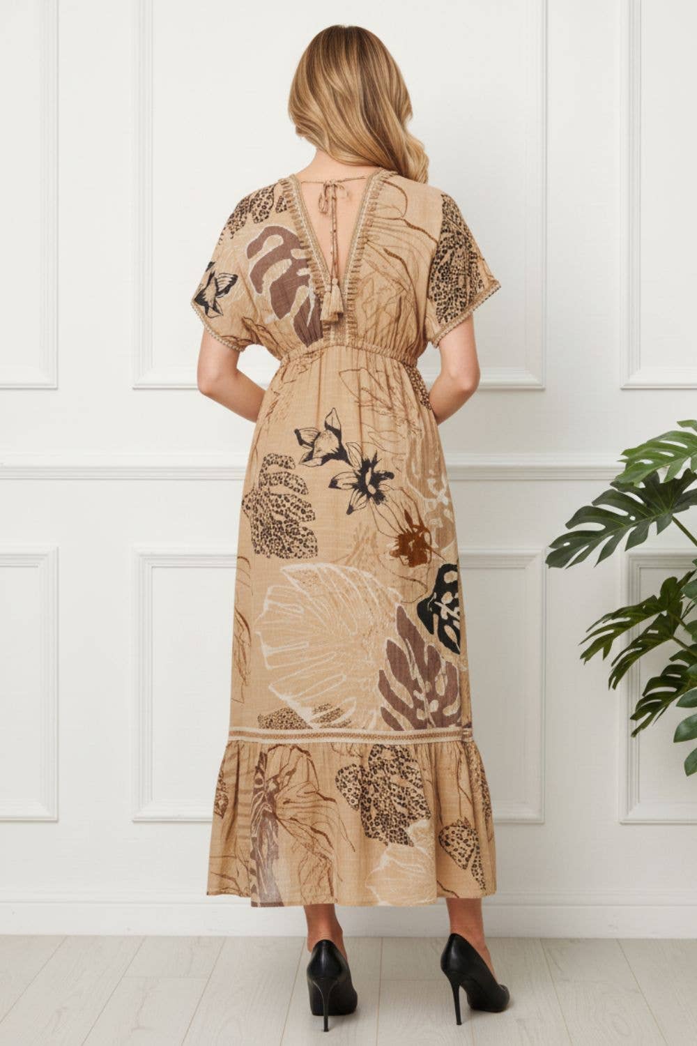 “Close-up of tassel tie front on beige printed maxi empire dress”