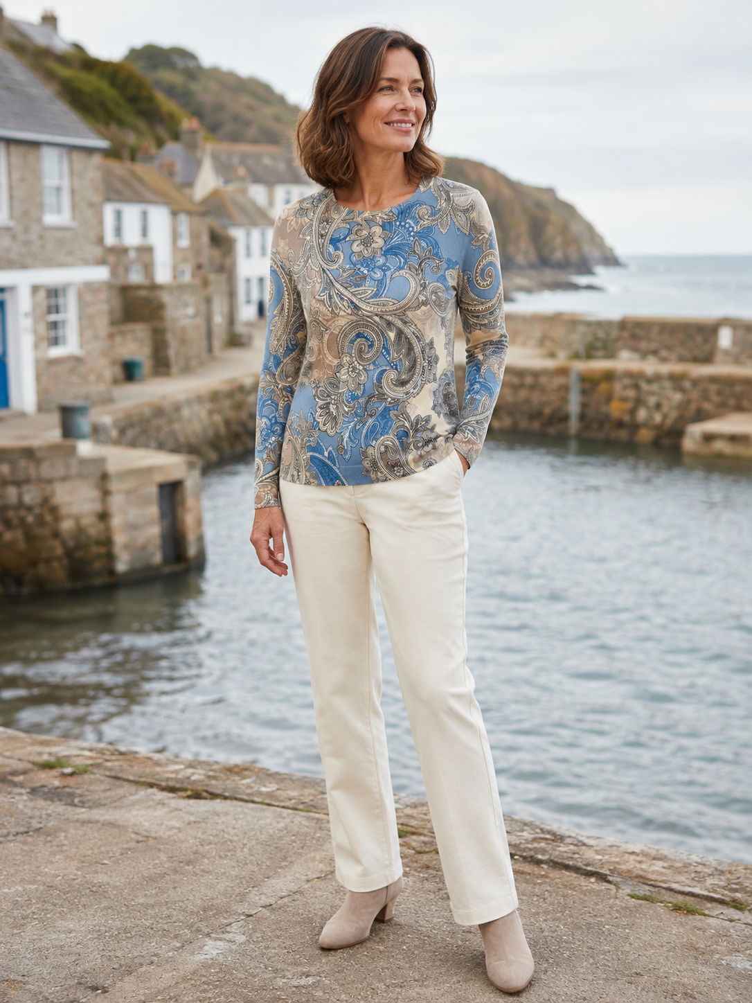 Woman in her 50s wearing the Alice Collins Esme Paisley Jumper by a coastal harbour